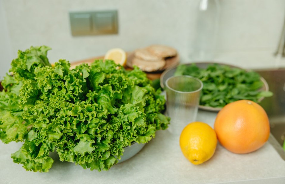 A vibrant display of fresh green lettuce and citrus fruits on a kitchen table.
